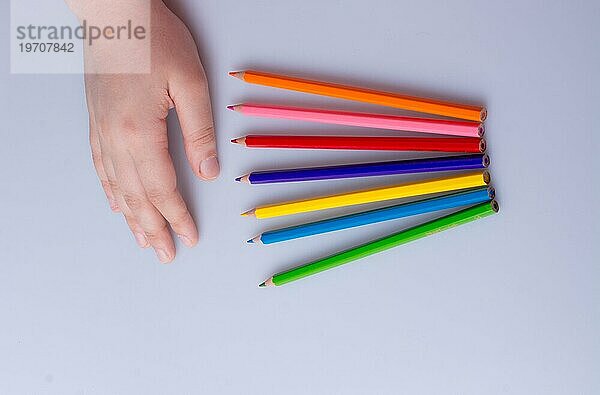 Hand hält Farbe Bleistifte auf einem weißen Hintergrund platziert
