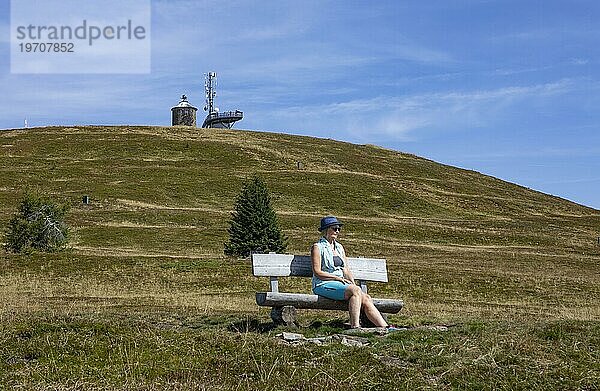 Wanderin sitzt auf einer Bank auf der Gerlitzen mit Blick zur Kanzelhöhe  Gerlitzen Alpe  Nockberge  Gurktaler Alpen  Kärnten  Österreich  Europa