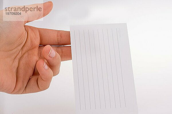 Hand hält ein Stück liniertes Papier auf weißem Hintergrund