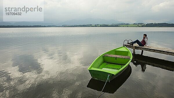 Frau 50+  Holzsteg  grünes Ruderboot  Hopfensee  Hopfen am See  bei Füssen  Ostallgäu  Allgäu  Bayern  Deutschland  Europa