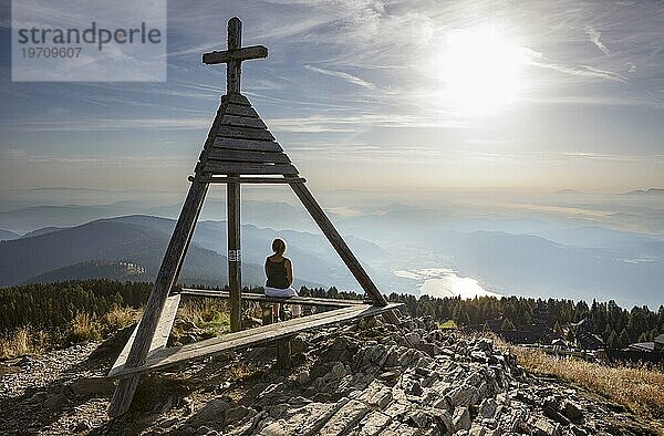 Wanderin sitzt beim Wetterkreuz Berger Alm auf der Gerlitzen  Gerlitzen Alpe  Nockberge  Gurktaler Alpen  Kärnten  Österreich  Europa