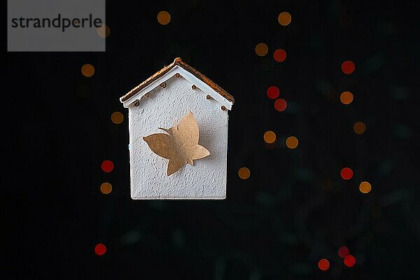 Papier Schmetterling auf einem Modell Haus auf einem Bokeh Licht