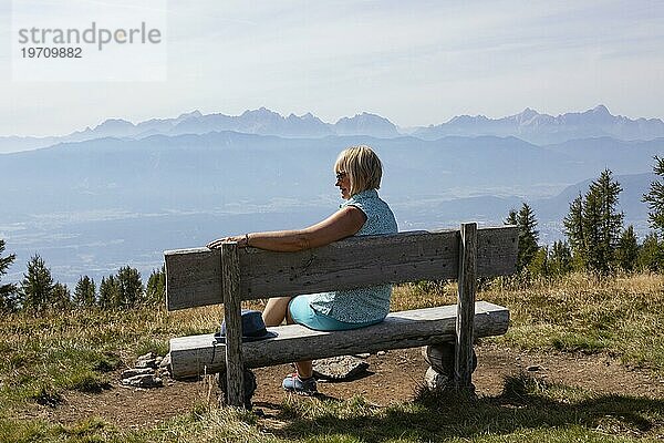 Wanderin sitzt auf einer Aussichtbank auf der Gerlitzen  Gerlitzen Alpe  Nockberge  Gurktaler Alpen  Kärnten  Österreich  Europa