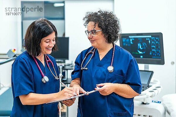 Ein lächelndes und gut gelauntes Team von Kardiologen erledigt Papierkram im Krankenhaus