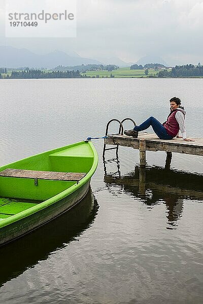 Frau 50+  Holzsteg  grünes Ruderboot  Hopfensee  Hopfen am See  bei Füssen  Ostallgäu  Allgäu  Bayern  Deutschland  Europa