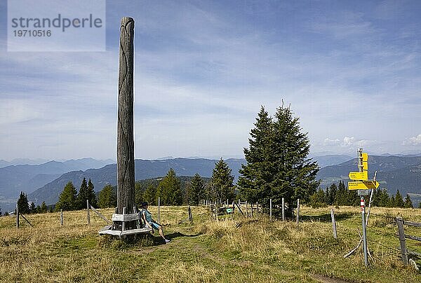 Wanderi sitzt bei einer kunstvollen Holzskulptur auf der Gerlitzen  Gerlitzen Alpe  Nockberge  Gurktaler Alpen  Kärnten  Österreich  Europa