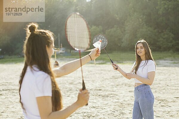 Mittlere Einstellung glückliche Mädchen spielen Badminton