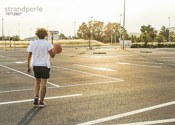 Mann spielt Basketballplatz während sonnigen Tag