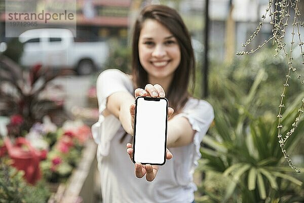 Glückliche Frau zeigt Mobiltelefon mit leerem weißen Bildschirm