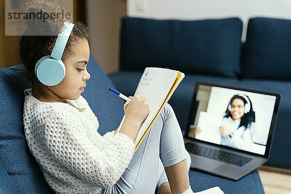 Seitenansicht kleines Mädchen in der Onlineschule mit Laptop und Kopfhörern