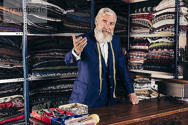 Porträt älterer männlicher Modedesigner  der jemanden in sein Geschäft einlädt