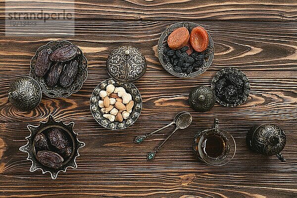 Erhöhte Ansicht ramadan frische Datteln Nüsse getrocknete Früchte Tee hölzernen Schreibtisch