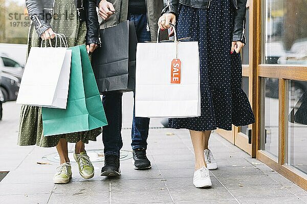 Niedriger Abschnitt Freunde zu Fuß Bürgersteig mit bunten Einkaufstaschen