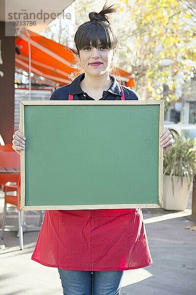 Weibliche Unternehmerin hält leere grüne Menütafel im Freien Café