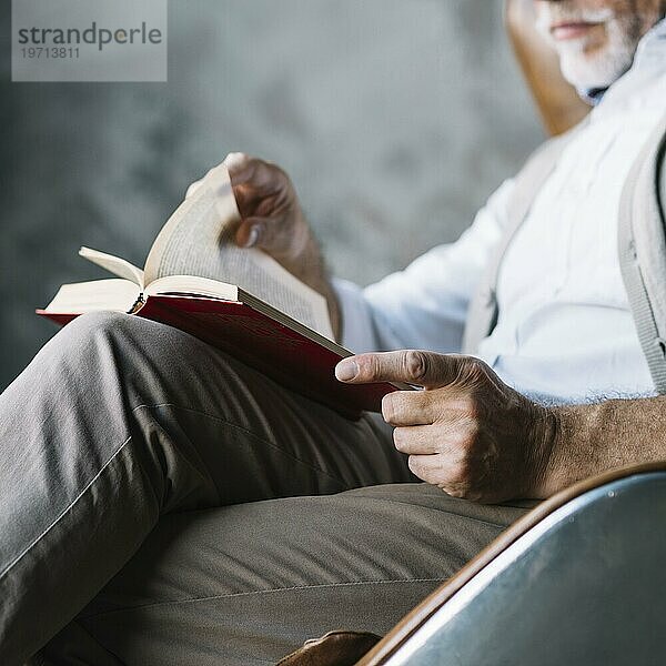 Close up Mann sitzt Stuhl lesen Buch