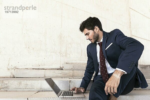 Mittlere Einstellung Mann sitzt auf einer Treppe mit Laptop