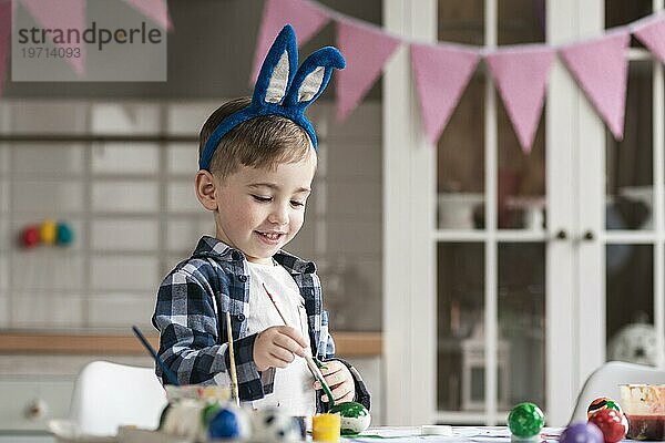 Porträt süßer kleiner Junge malt Eier Ostern