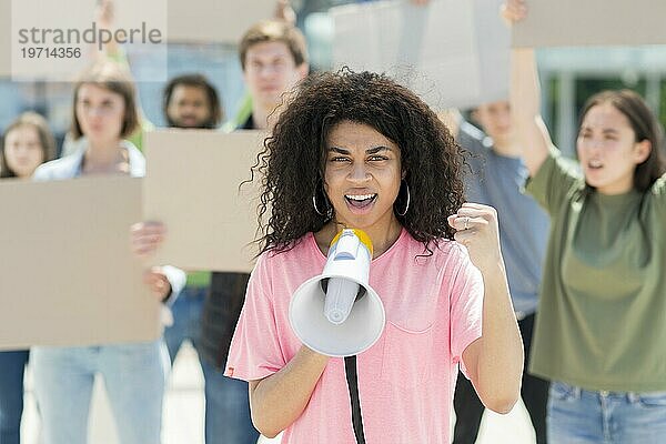 Frau mit lockigem Haar protestiert mit Megaphon