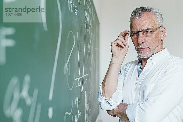 Konzentrierter Mathelehrer mit Blick auf die Kreidetafel
