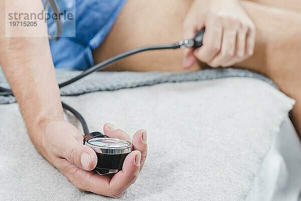 Close up Mann s Hand sitzt Bett mißt seinen Blutdruckmessgerät