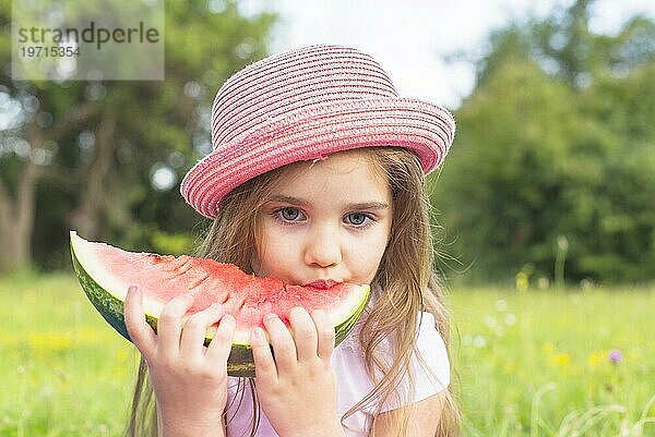 Nettes Mädchen trägt rosa Hut essen Wassermelone Scheibe Park