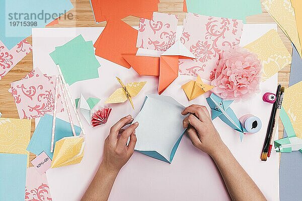 Erhöhte Ansicht menschliche Hand machen Origami Papier Kunst Holztisch