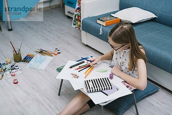 Mädchen Malerei Papier Tisch mit Satz Stifte Zimmer mit Wasserfarben Boden