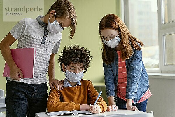 Frontansicht Kinder mit medizinischen Masken beim Lernen in der Schule