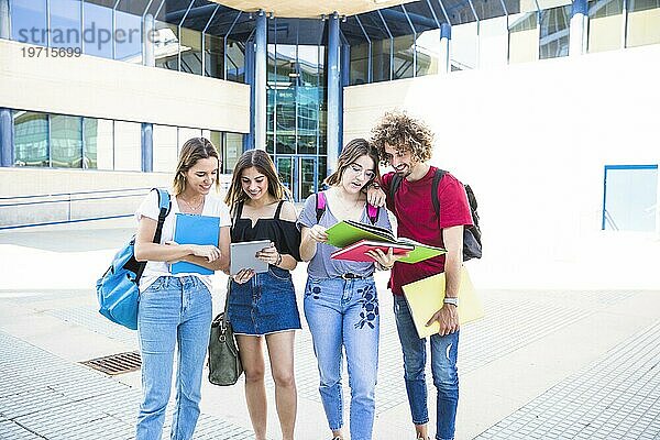 Gut gelaunte Studenten mit Tablet Lehrbüchern in der Nähe des Universitätsgebäudes