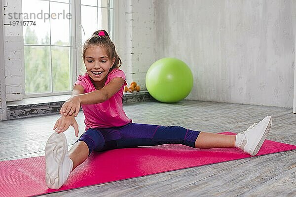 Porträt lächelnd Mädchen sitzen Übungsmatte Stretching seine Hand Bein