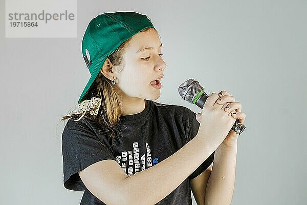 Mädchen singt Lied mit Mikrofon grauem Hintergrund