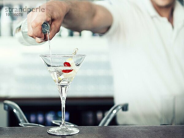 Unbekannter Barmann schenkt Cocktailglas ein