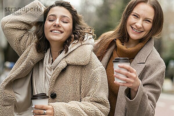 Smileyfrauen mit Kaffeetassen im Freien