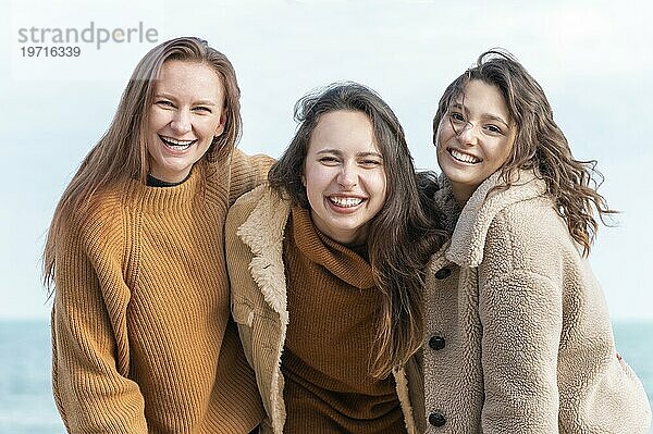 Lächelnde Frauen posieren zusammen am Meer