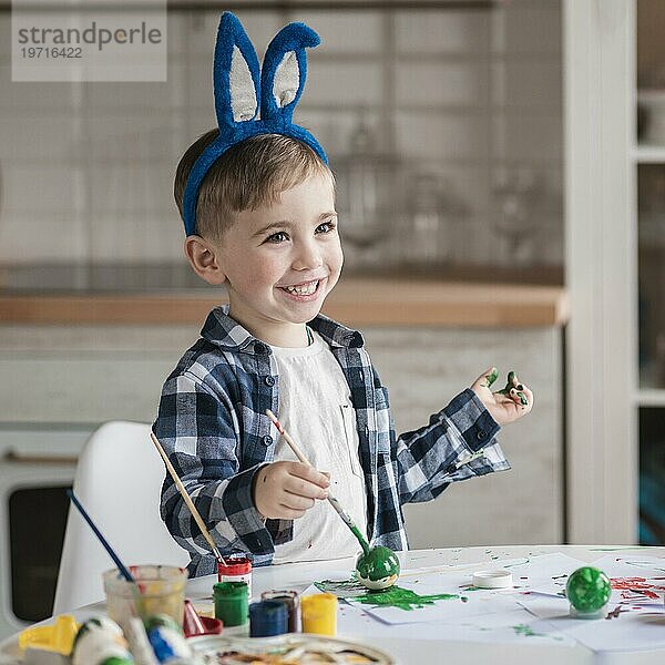 Porträt eines bezaubernden kleinen Jungen  der mit Farbe spielt