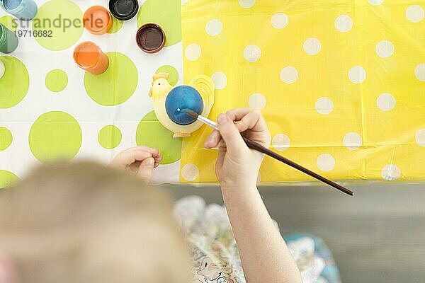 Mädchen malt Ei mit Pinsel