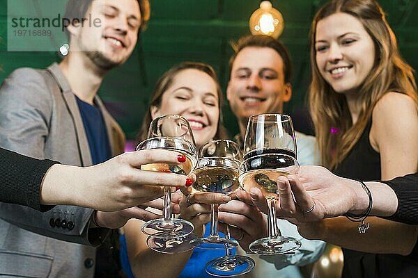 Lächelnde männliche weibliche Freunde stoßen mit Cocktails in einer Bar an