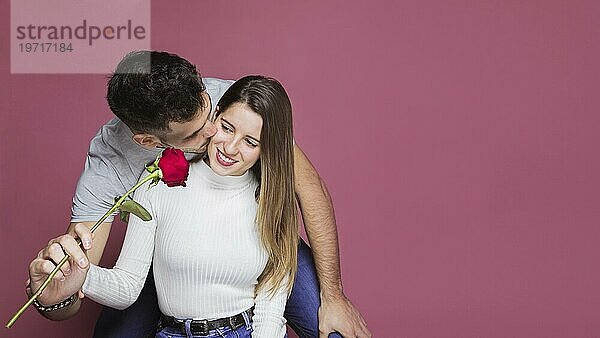 Guy küssen präsentiert frische Rose attraktiv fröhliche Dame