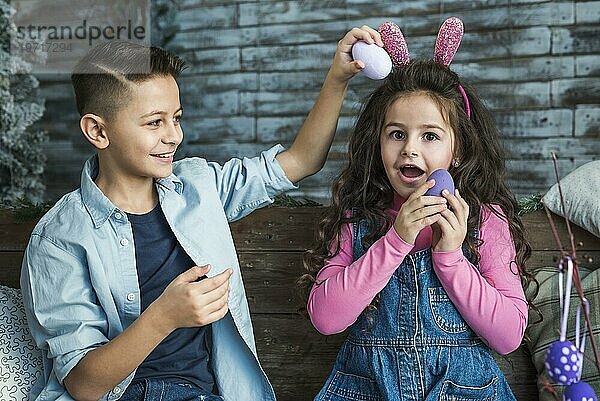 Mädchen Hasenohren Junge spielt mit Ostereiern