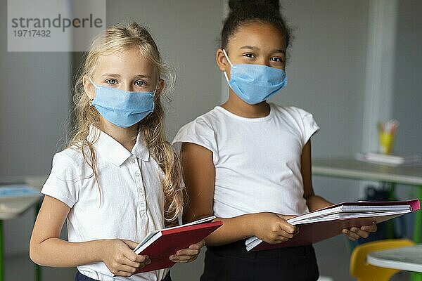 Mädchen tragen medizinische Masken Klasse