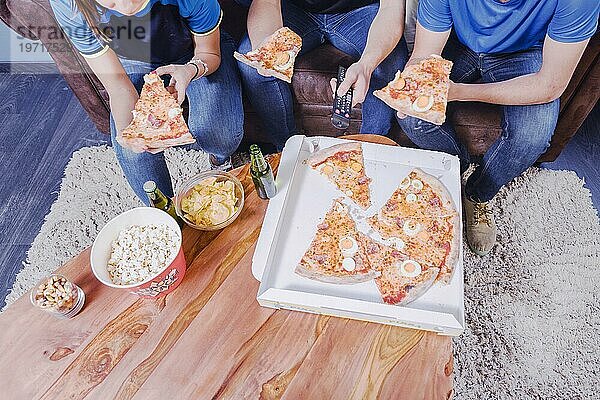 Freunde essen Pizza und schauen Fußball