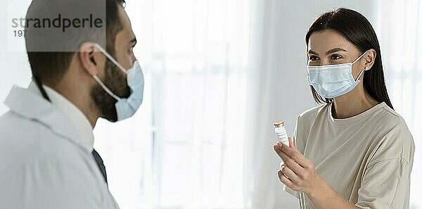 Patient und Arzt im Gespräch  während er medizinische Masken trägt