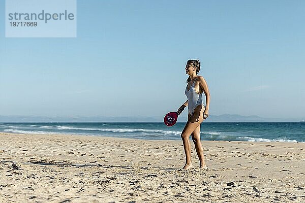 Glückliche junge Frau beim Tennisspielen am Meeresufer