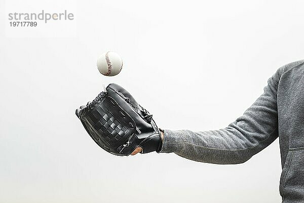 Mann hält Handschuh und wirft Baseball