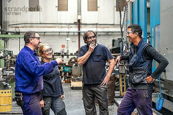 Ein Team von Arbeitern lacht bei der Arbeit in einer Metallfabrik im Bereich der numerischen Steuerung und spricht