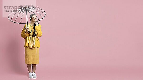 Frau posiert  während sie einen Regenschirm mit Kopierraum hält