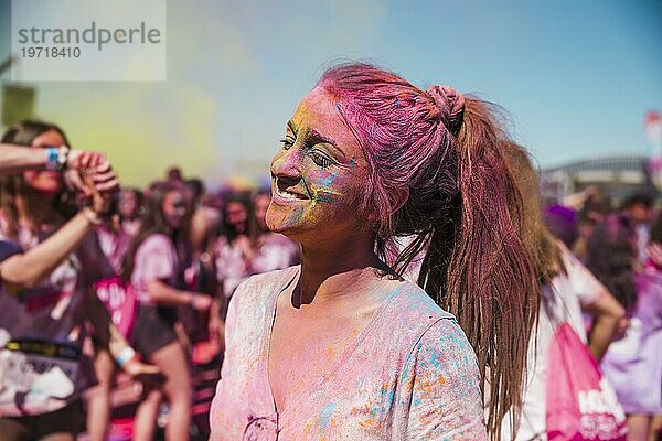 Porträt lächelnde junge Frau mit Holi Farbe bedeckt