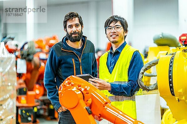 Porträt zweier junger multiethnischer Ingenieure in der Industrieroboterbranche  die in die Kamera schauen und lächeln