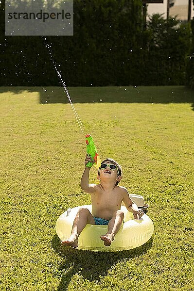 Junge Schwimmer spielt mit Wasserpistole