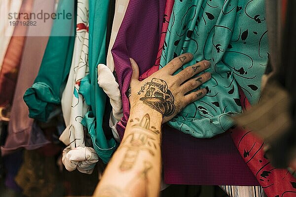 Close up Mann mit Tattoo seine Hand berühren Hemden angeordnet Schiene